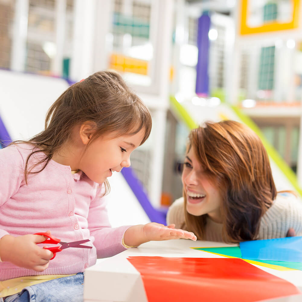 Teacher with child cutting paper