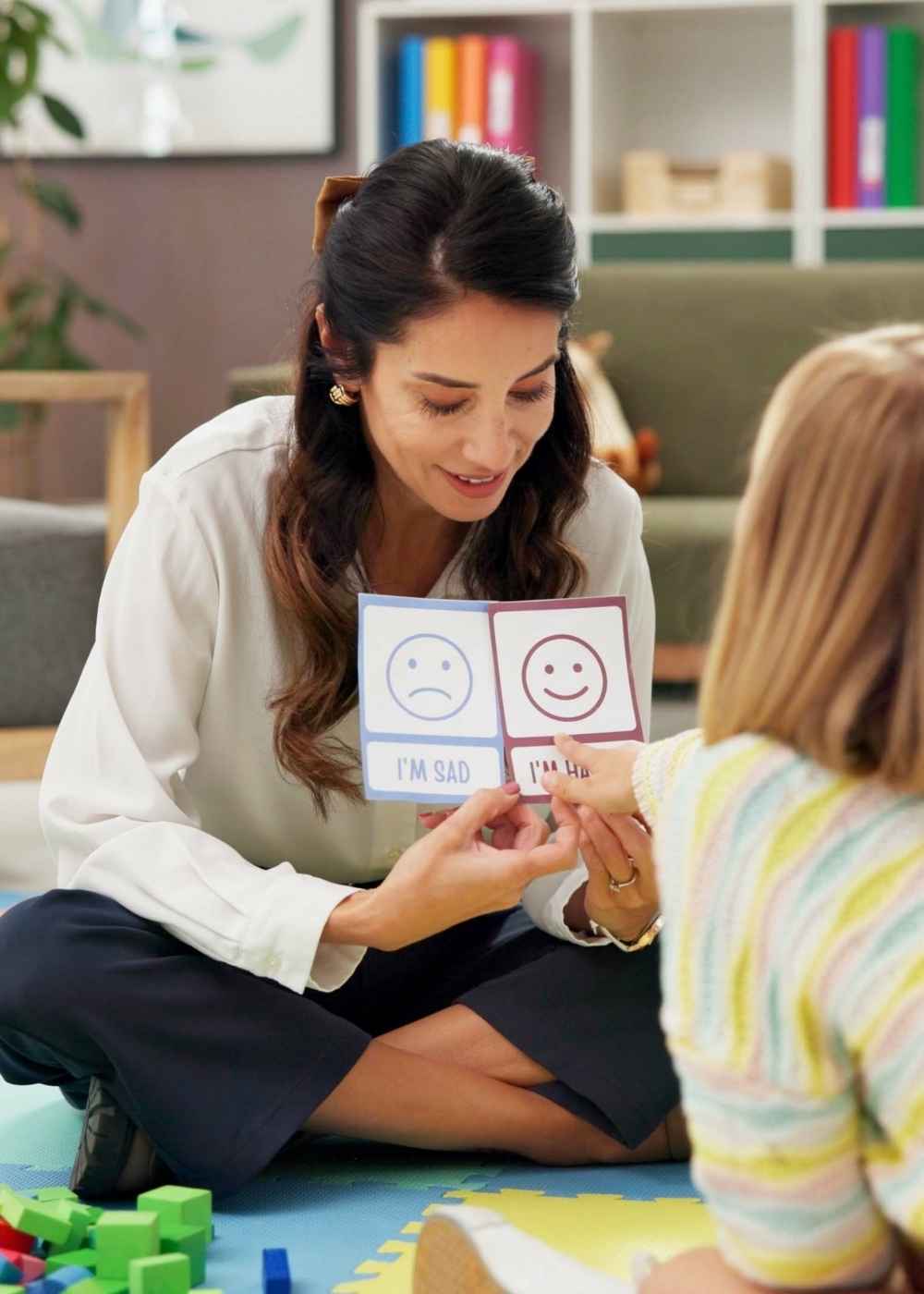 ABA therapist helping a child identify emotions using visual cards during an autism therapy session.